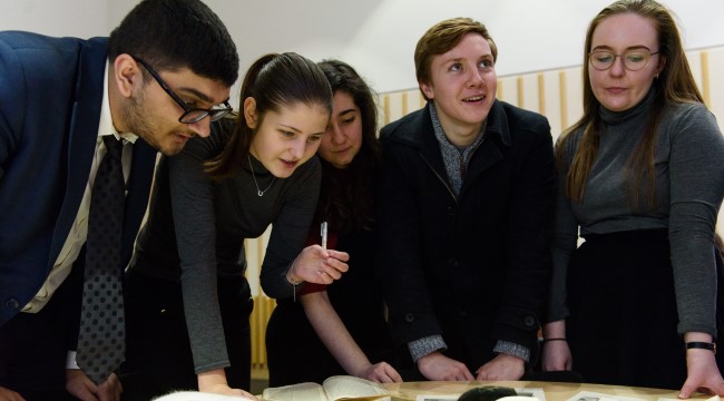 A group of people crowd together over a table covered in books. Photo: Richard Eaton