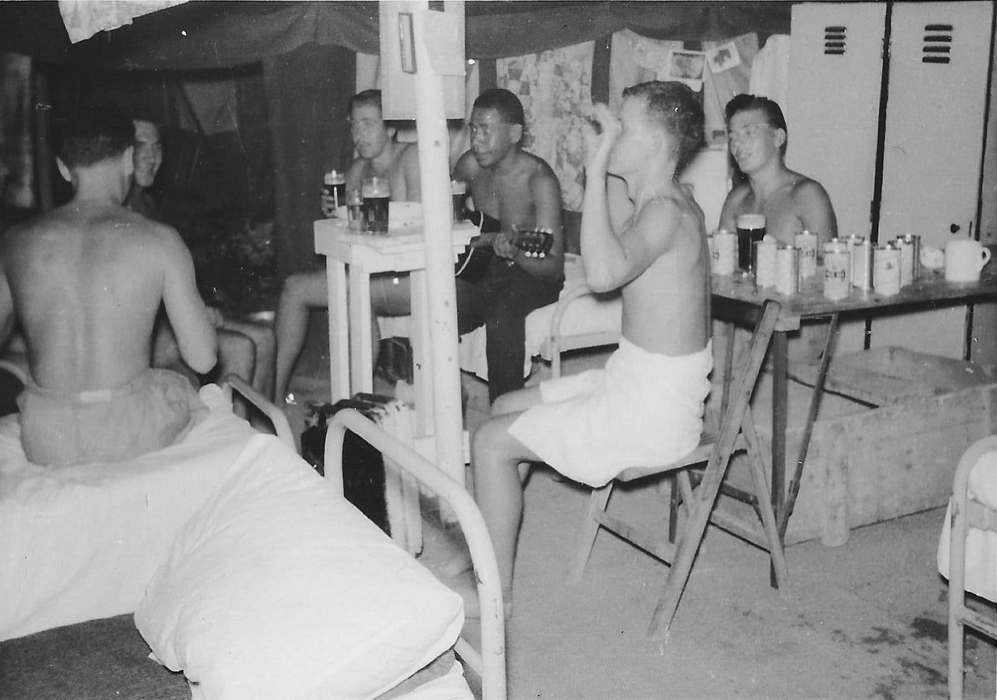 Black and white photo of men drinking beer and playing the guitar.
