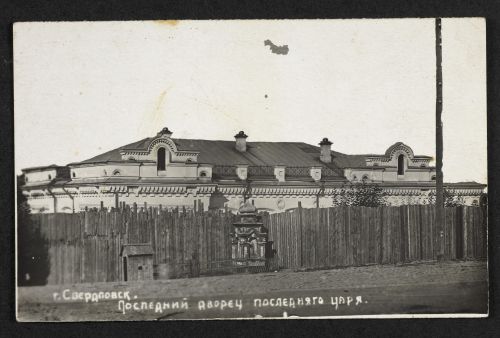 Photograph of the Ipatiev house behind a high wooden fence.