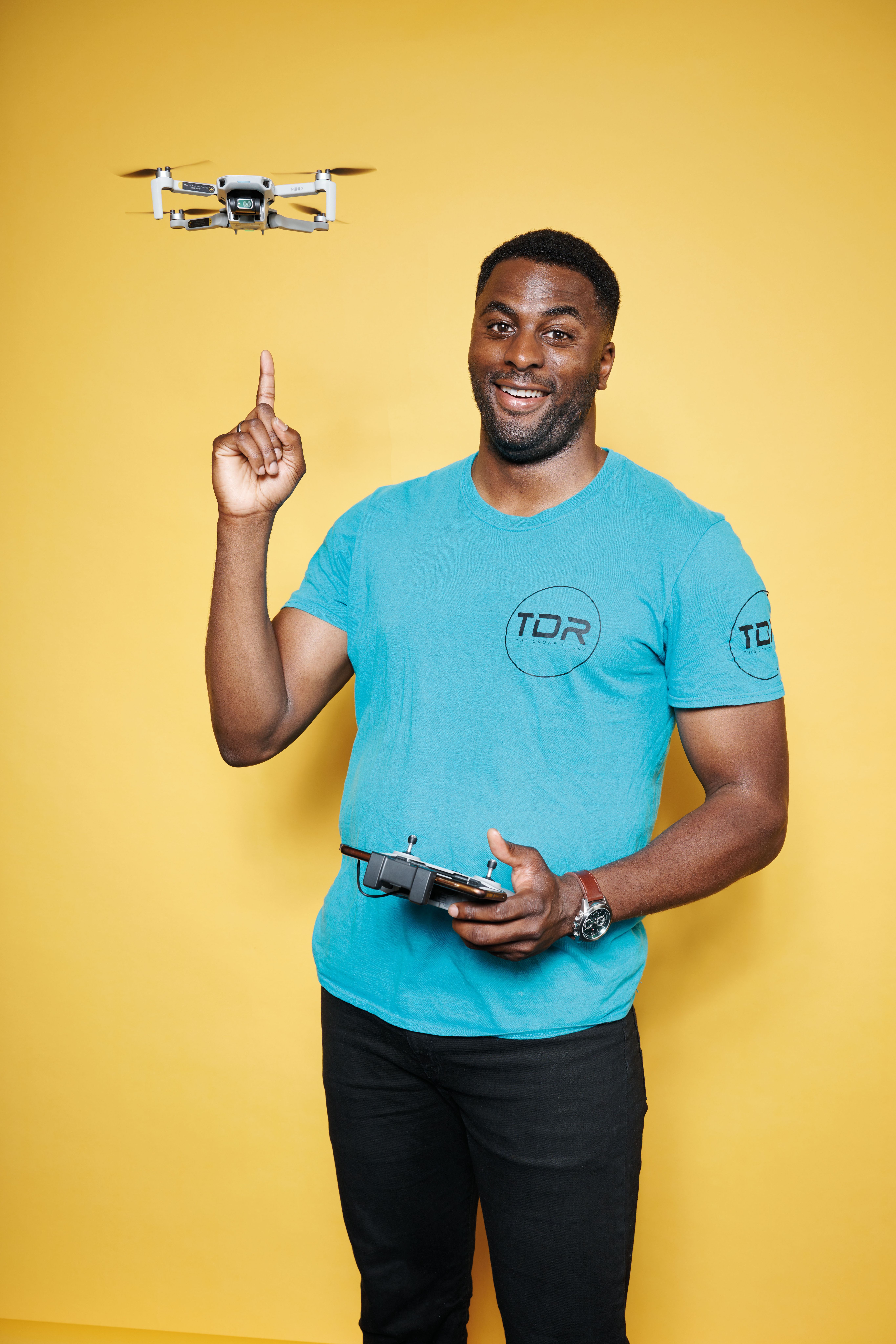 William Arinze pointing to a drone hovering by his head.