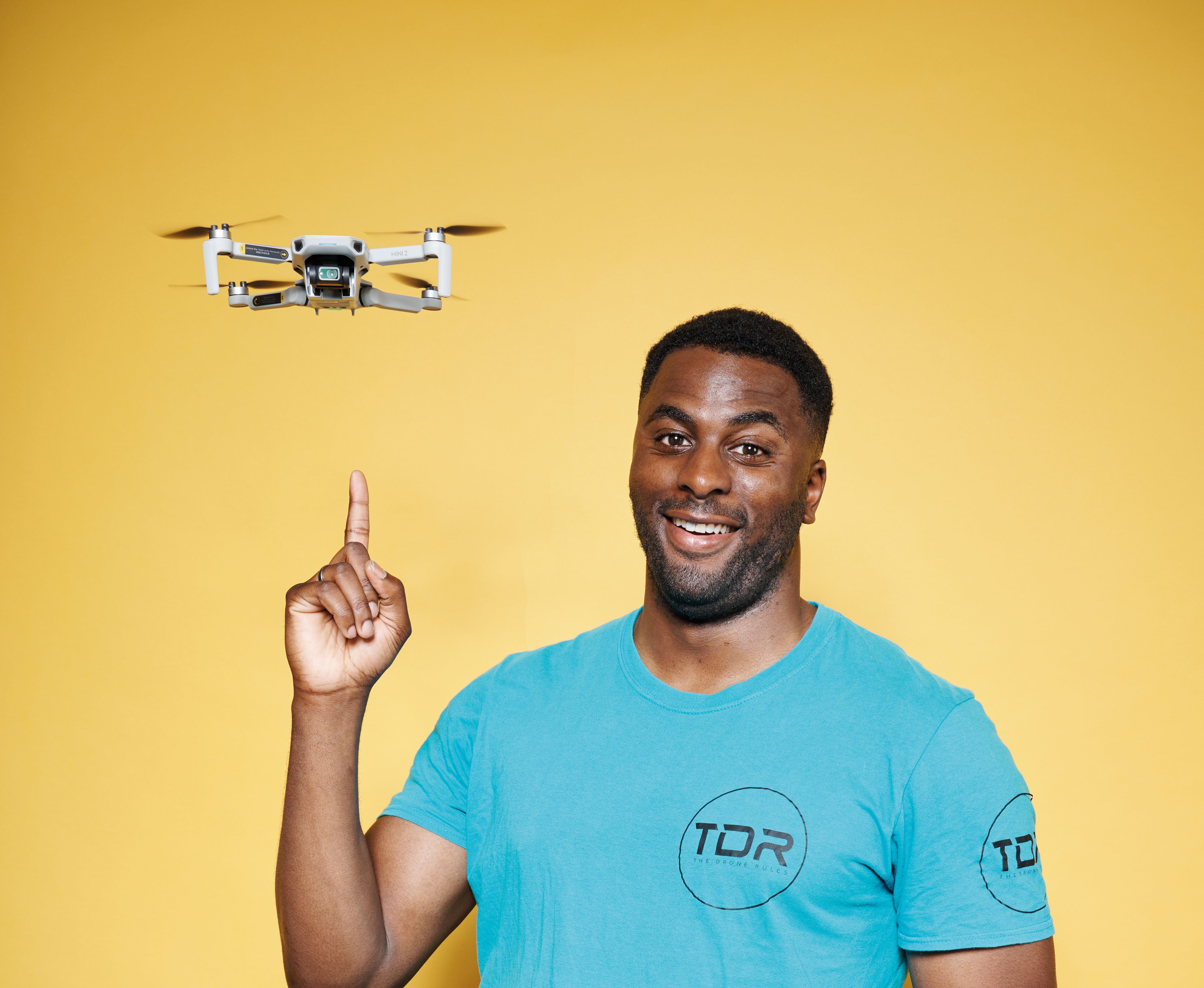 William Arinze pointing to a drone hovering by his head.