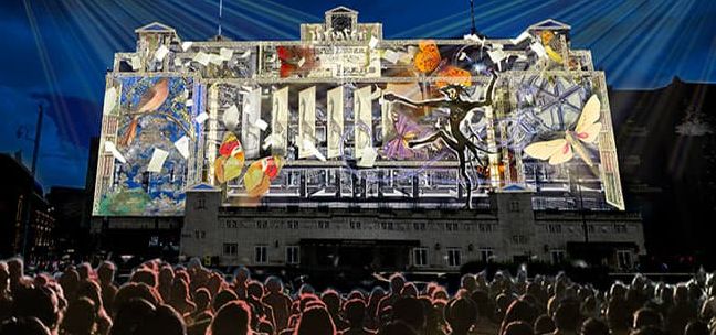 An outdoor light show with images projected onto a building.