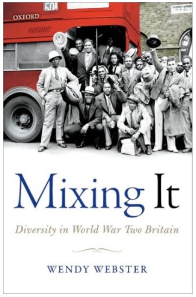 A group of people posing by a red bus - they are waving hats