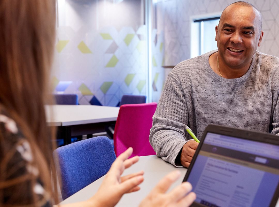 Woman with laptop talking to man.