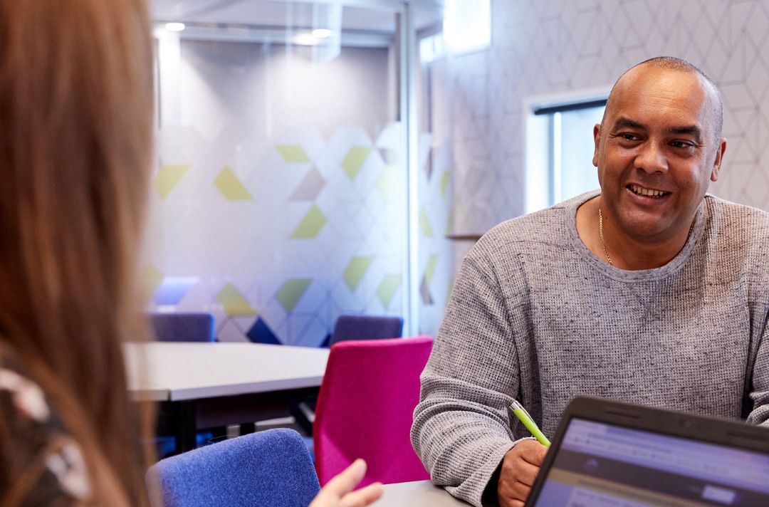 Woman with laptop talking to man.