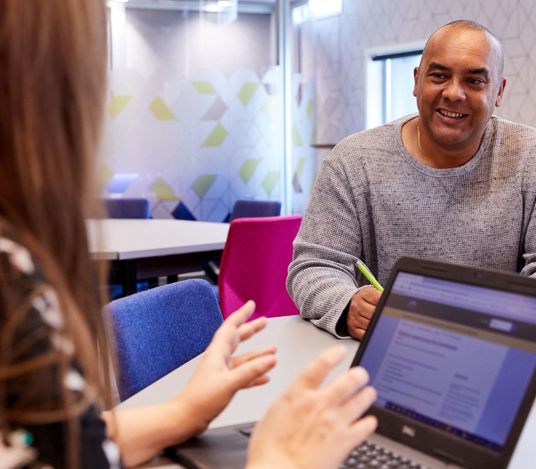 Woman with laptop talking to man.