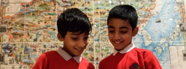 Two schoolboys with a map behind them.