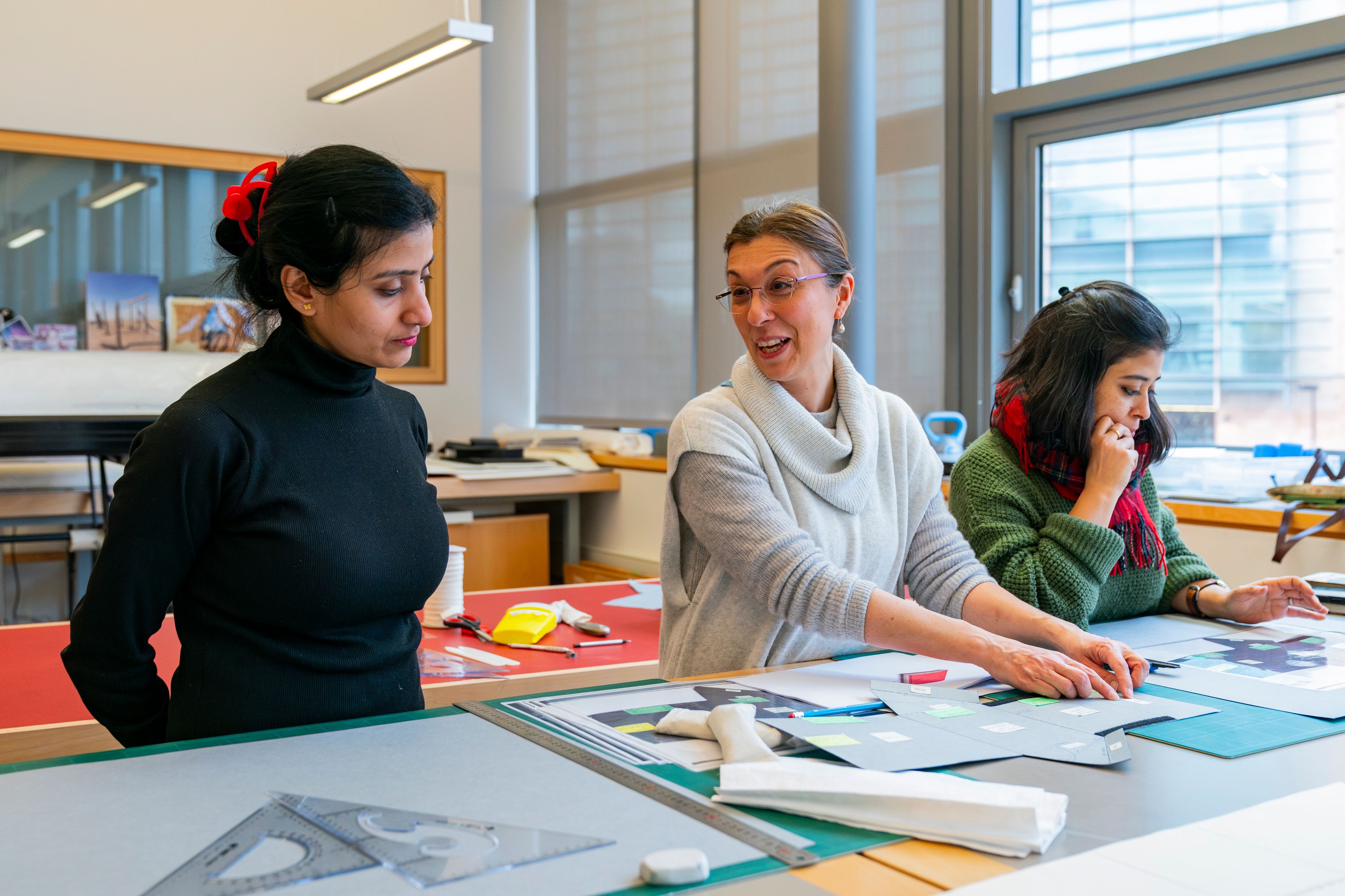 Three women at a workbench doing conservation work.