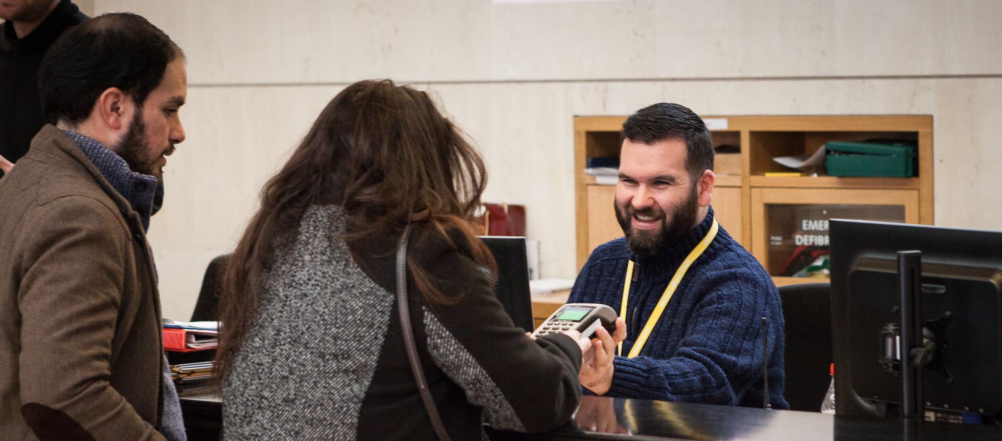 Visitors talking to a man behind the kiosk at the British Library.