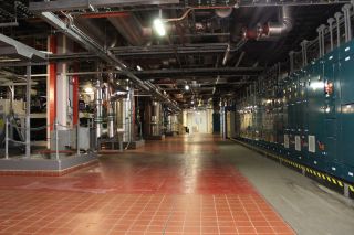A room with pipes across the ceiling and a red tiled floor