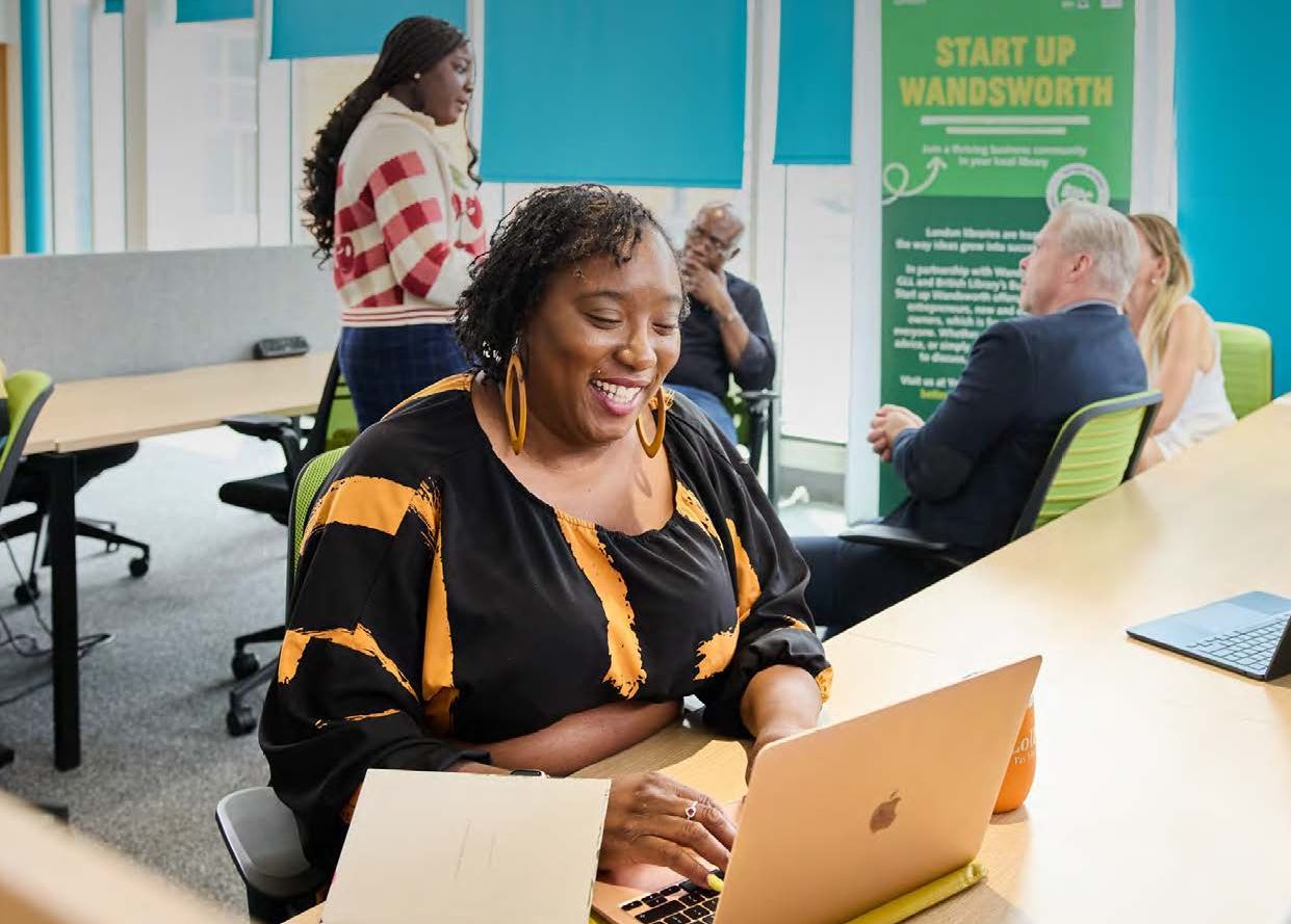Woman with laptop at desk in library.