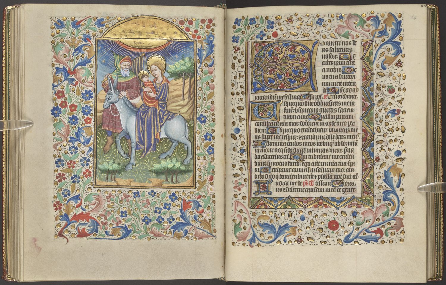 An opening from a medieval manuscripts, showing a full-page illustration of the Flight of Mary and Joseph into Egypt, with foliated borders in colours and gold.