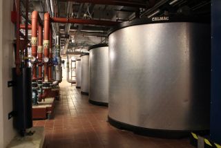Large metal vats in a room with pipework on the ceiling