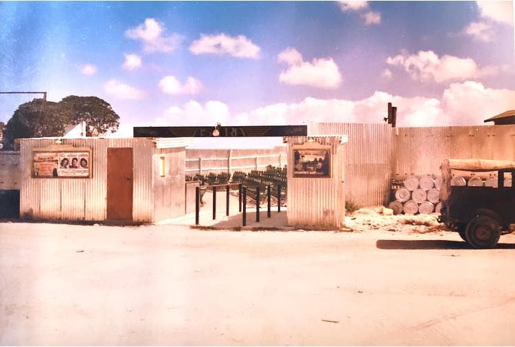 A view from the outside of the open-air cinema. A sign with the name 'Astra' spans the entrance gates.