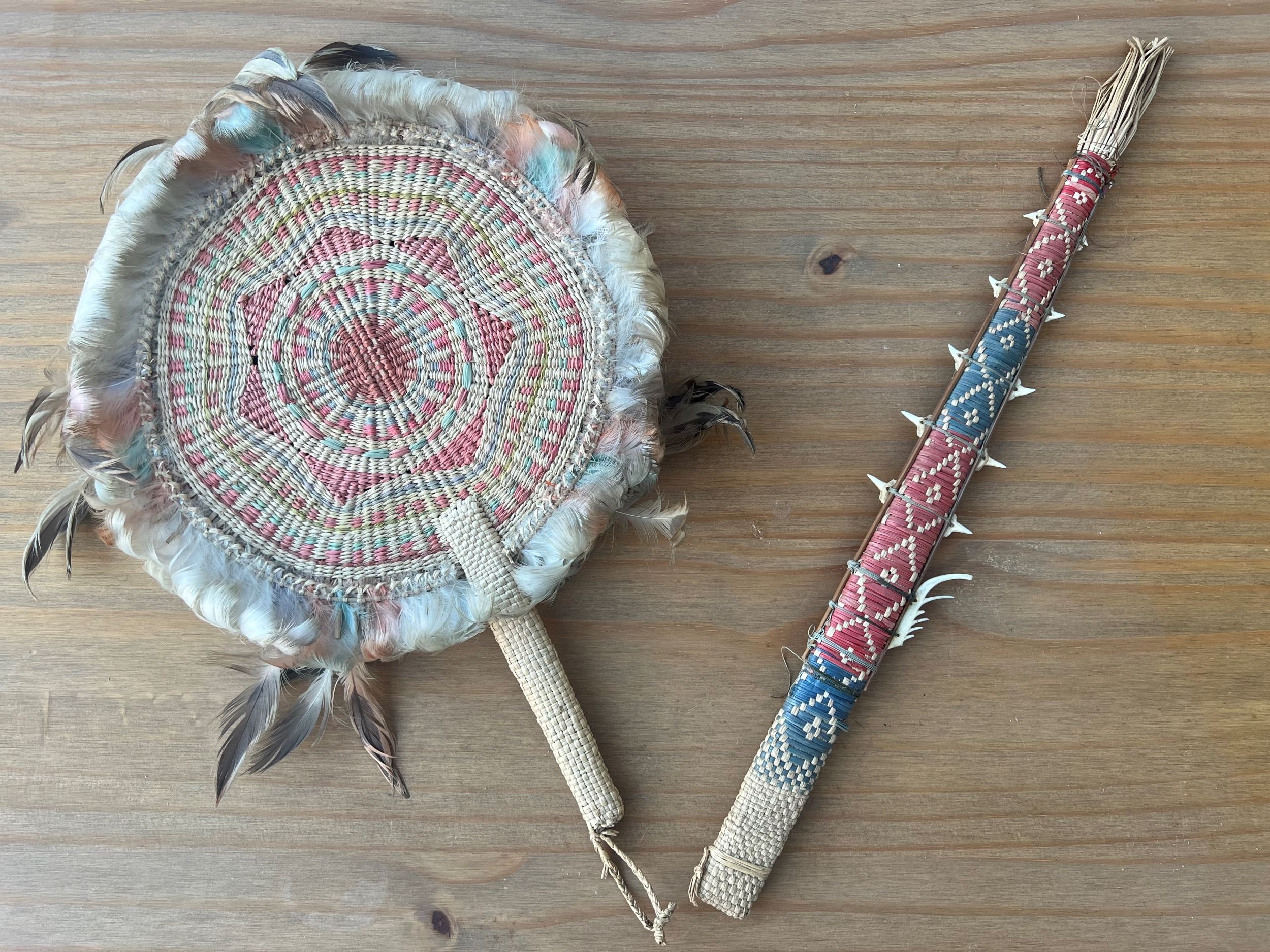 Woven crafts in the form of a fan and sword, adorned with bird feathers and shark teeth respectively.
