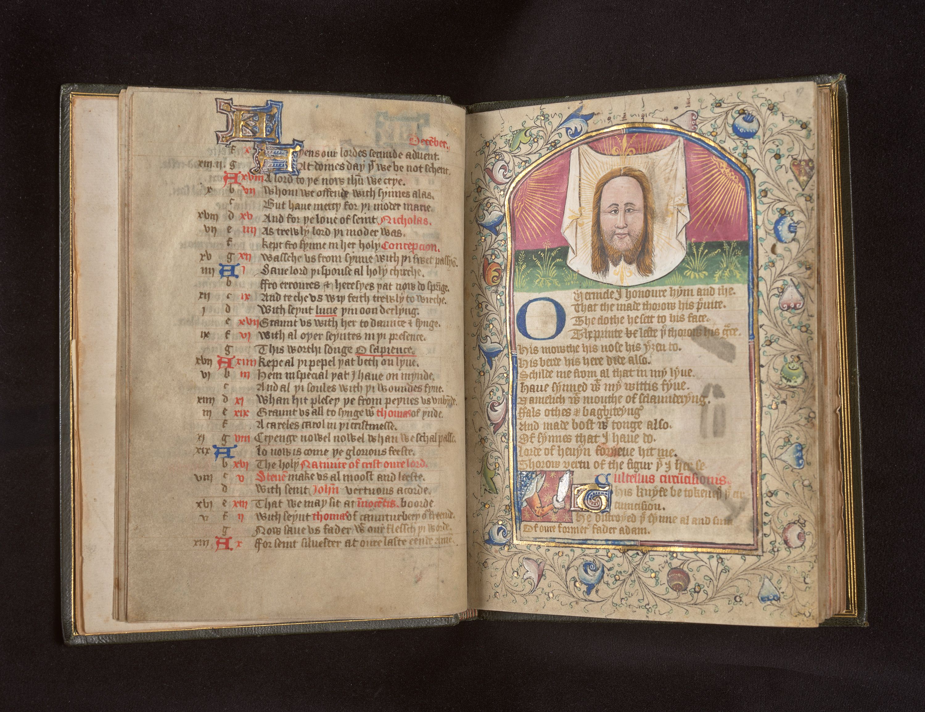 An open manuscript with writing on both pages and an illustrated face at the top of the right page