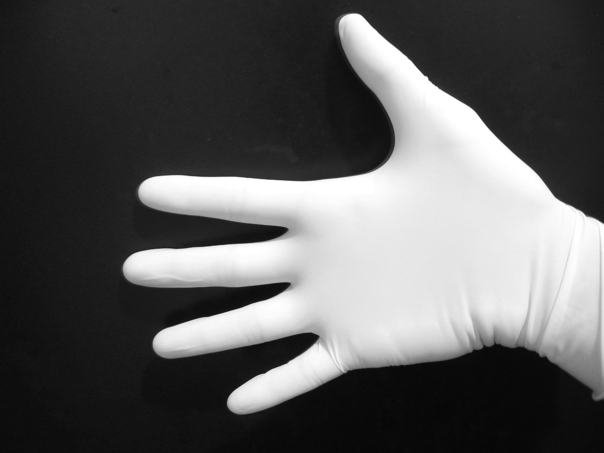 A photo of a hand wearing a white glove, fingers splayed, on a black background.