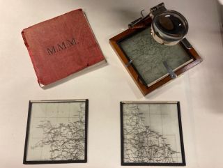 Photo of a book, three glass map plates and a frame with a magnification glass with which to view the plates