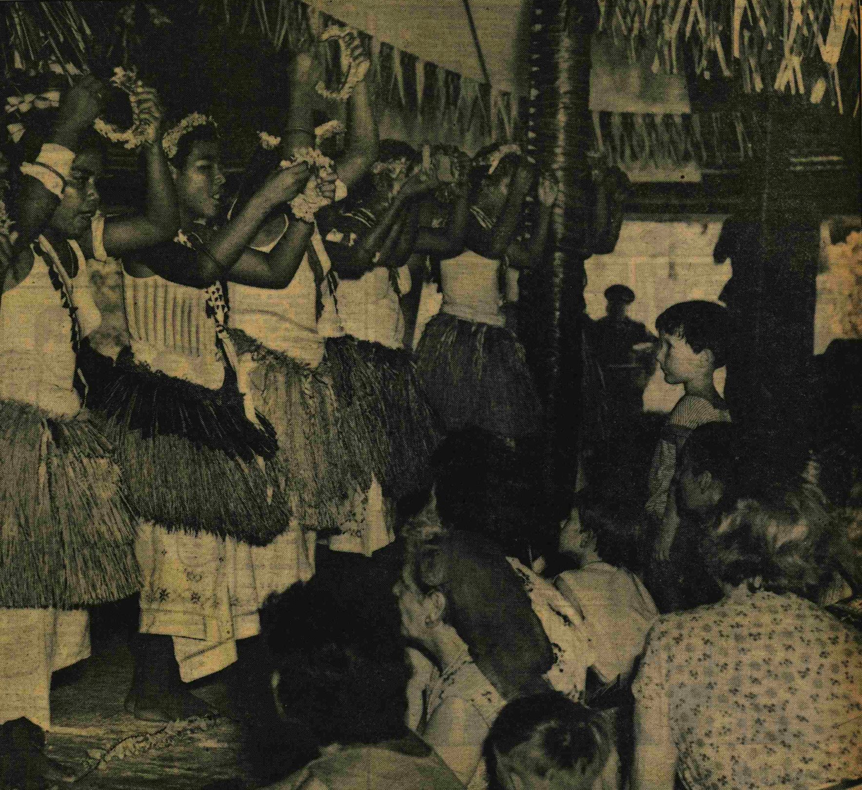 Families watch the I-Kiribati dancers in a maneaba. A boy of no more than 10 years old is standing and looks enchanted by the performance.