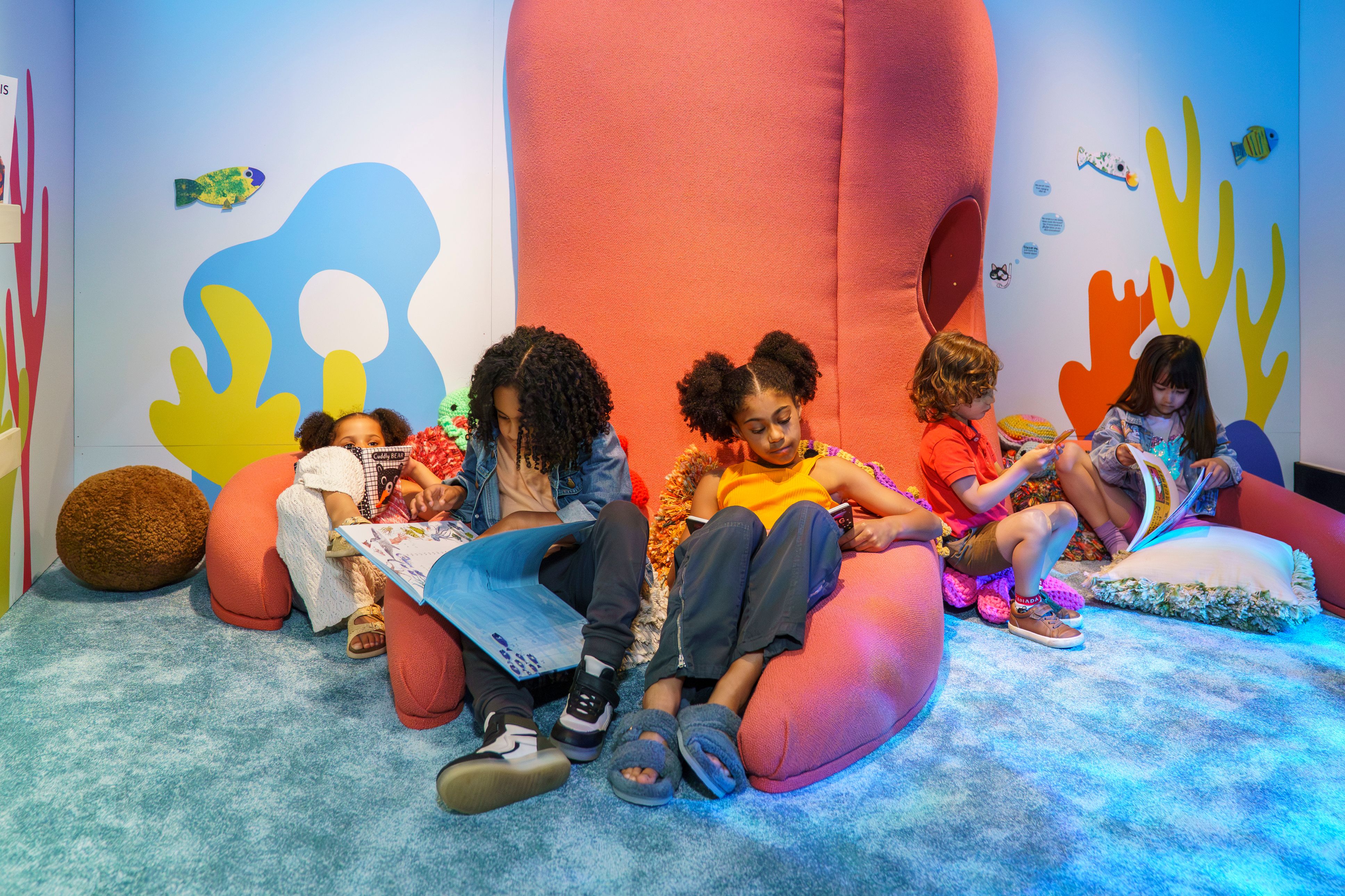 Two children sitting on inflatables, reading.