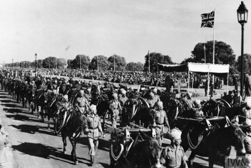 Indian Army mountain guns carried on pack mules pass the saluting base during the Victory Parade in Delhi, with a Union Jack flag flying in the background