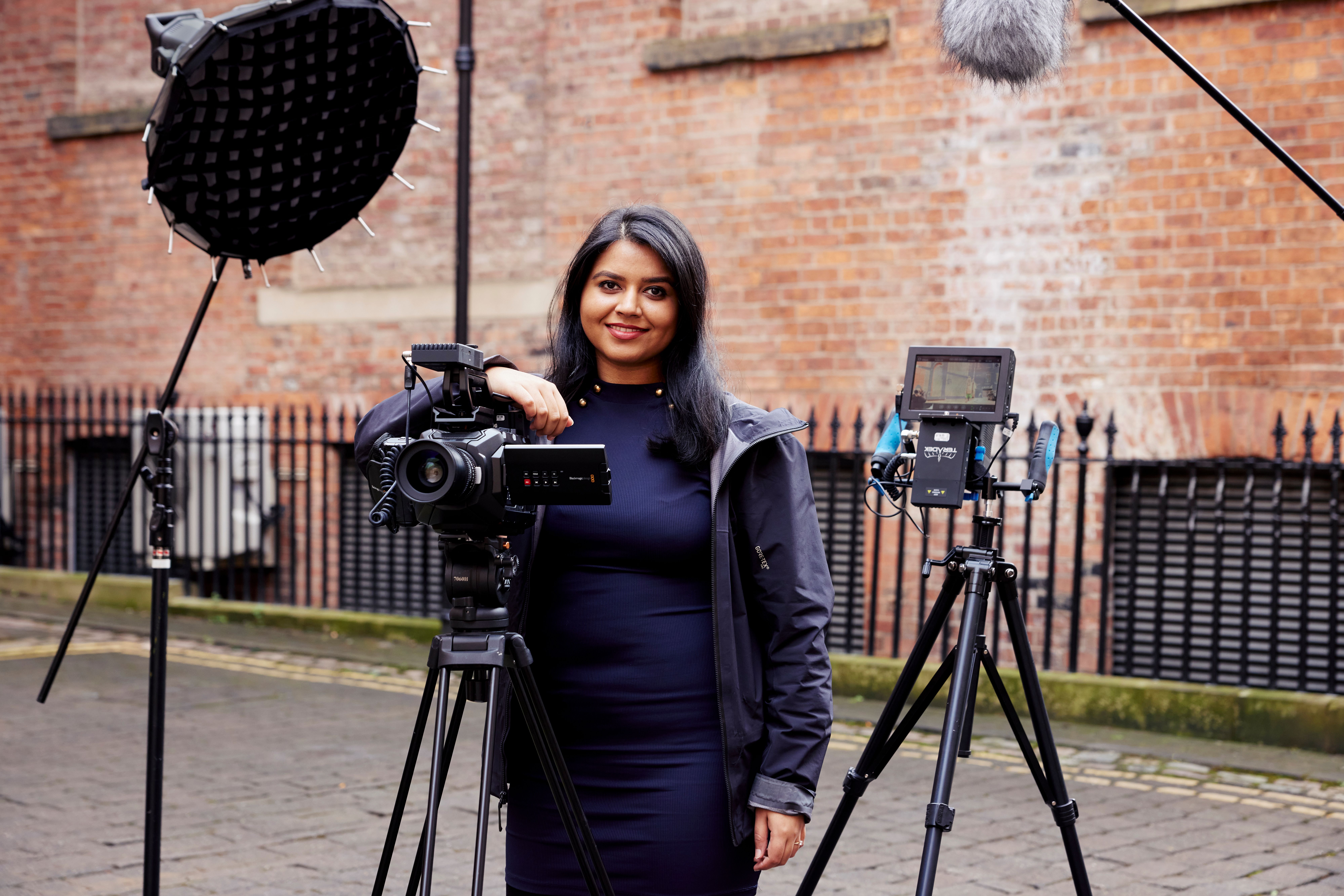 Suman Hanif standing with photography equipment.