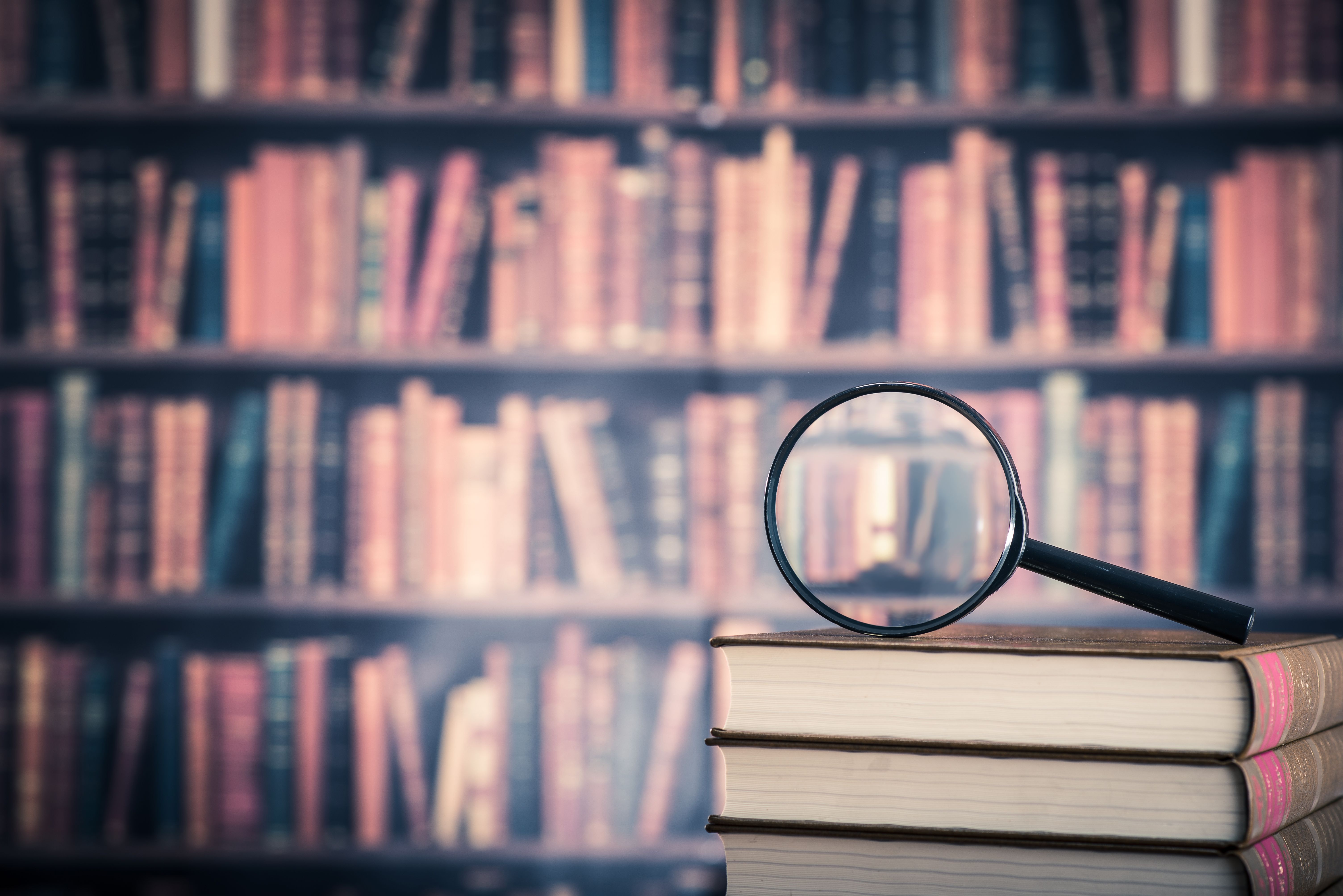 Magnifying glass with bookshelves in background.