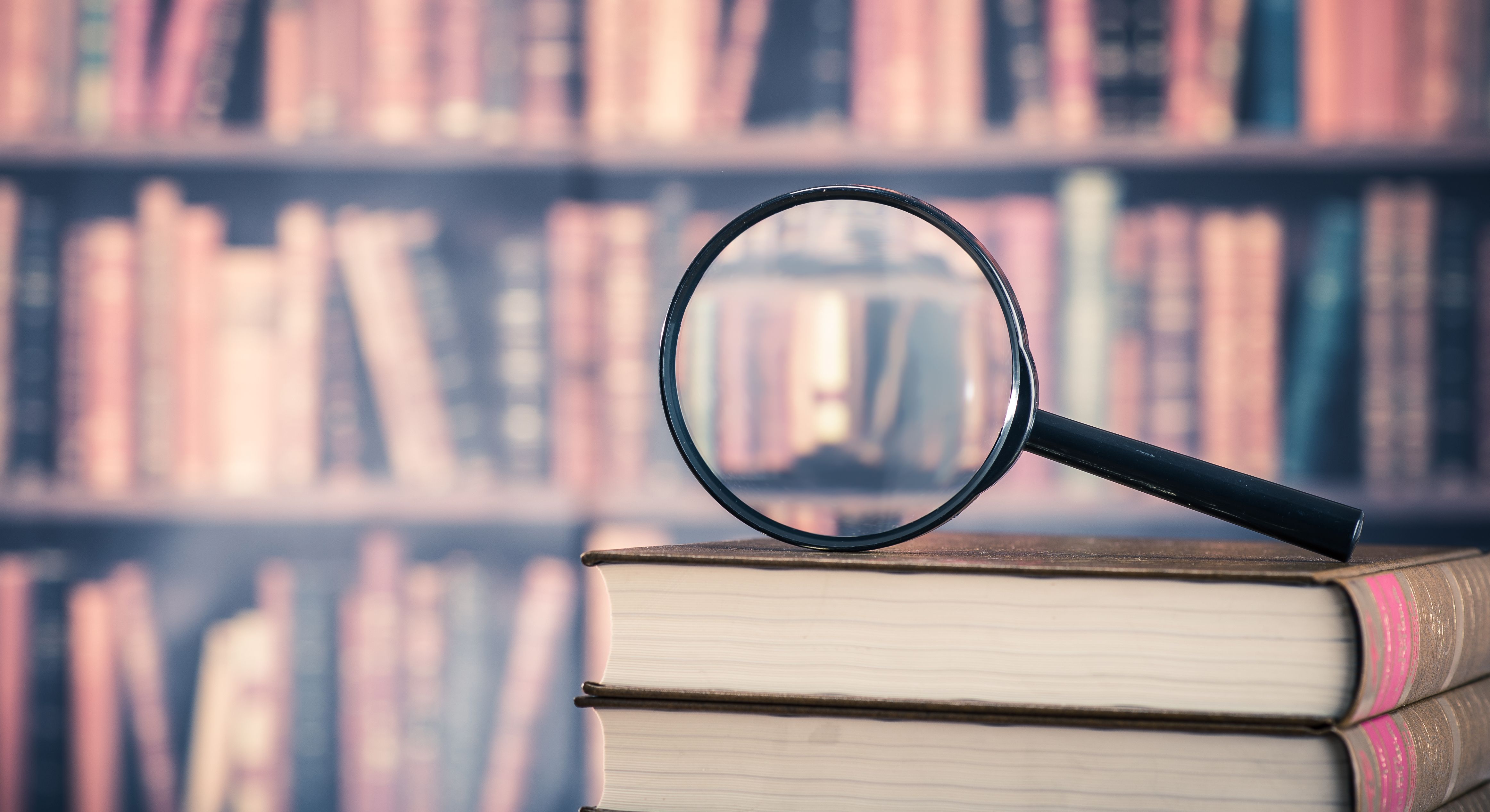 Magnifying glass with bookshelves in background.