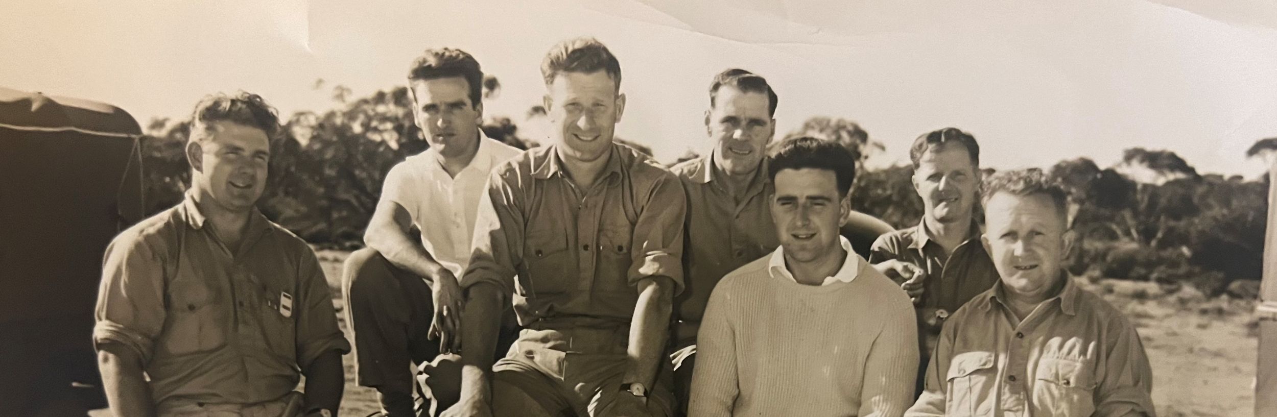 Ken Sims poses on the bonnet of a Holden SJ sedan with his comrades.
