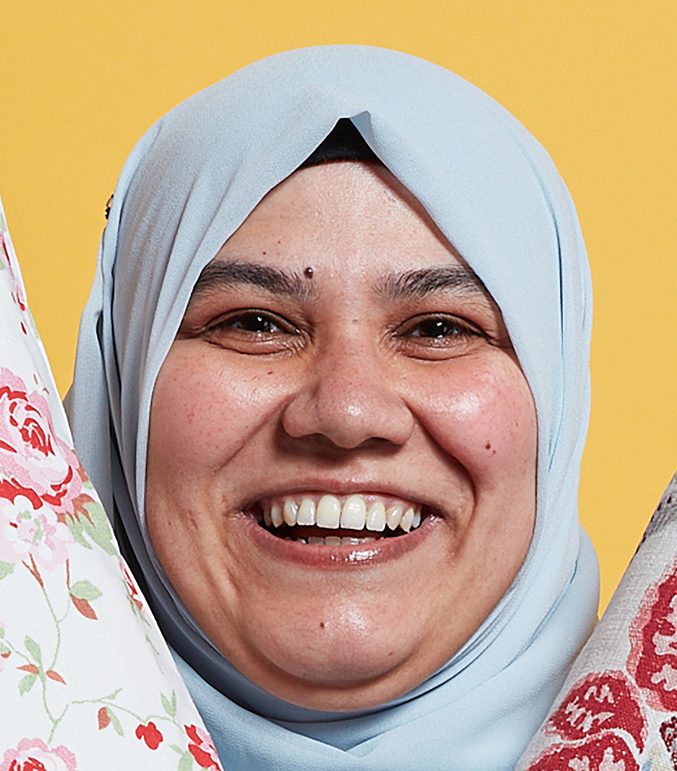 A business woman smiles while holding two cushions in the air to show off her products.