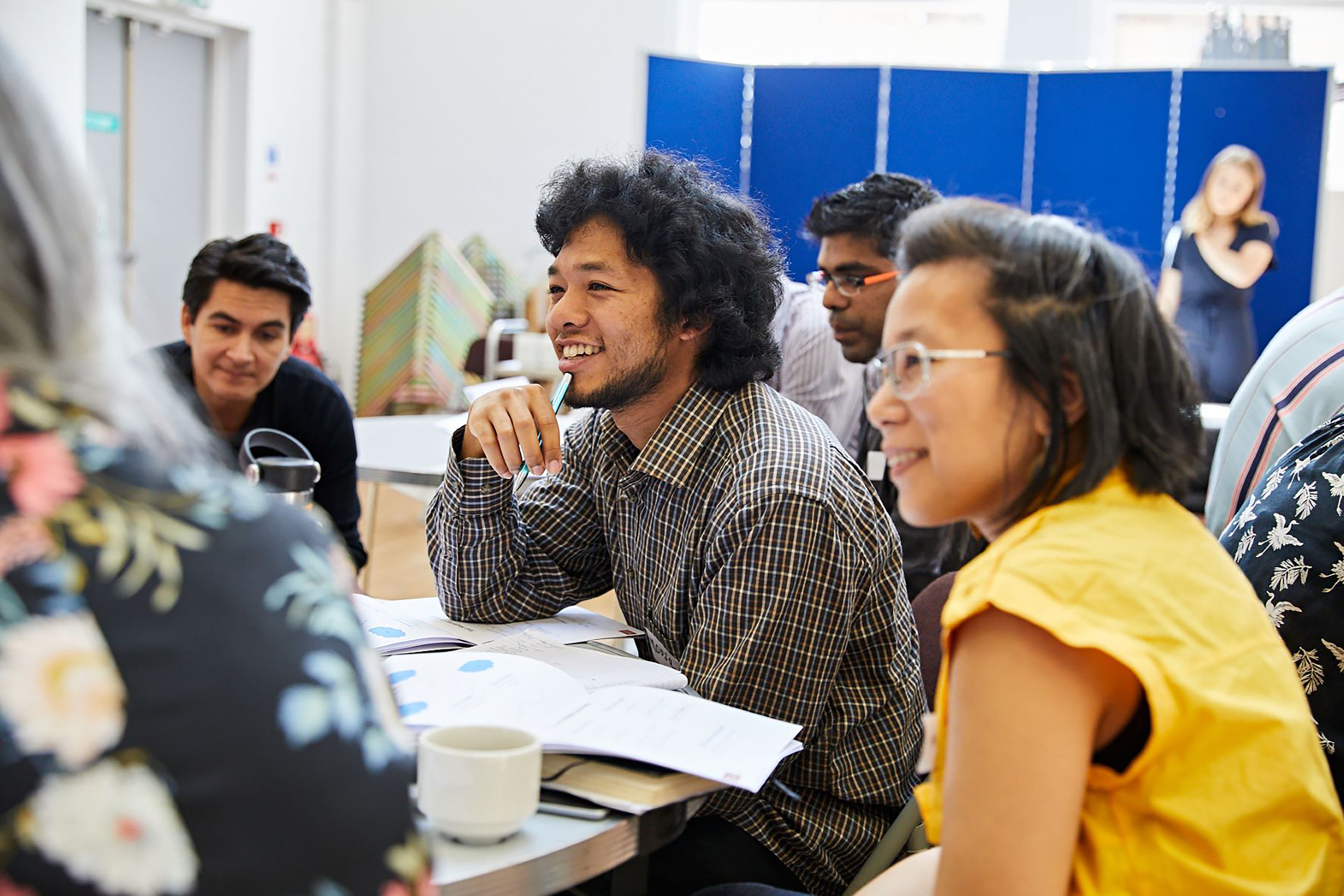 A group of people sit around a table at a workshop.