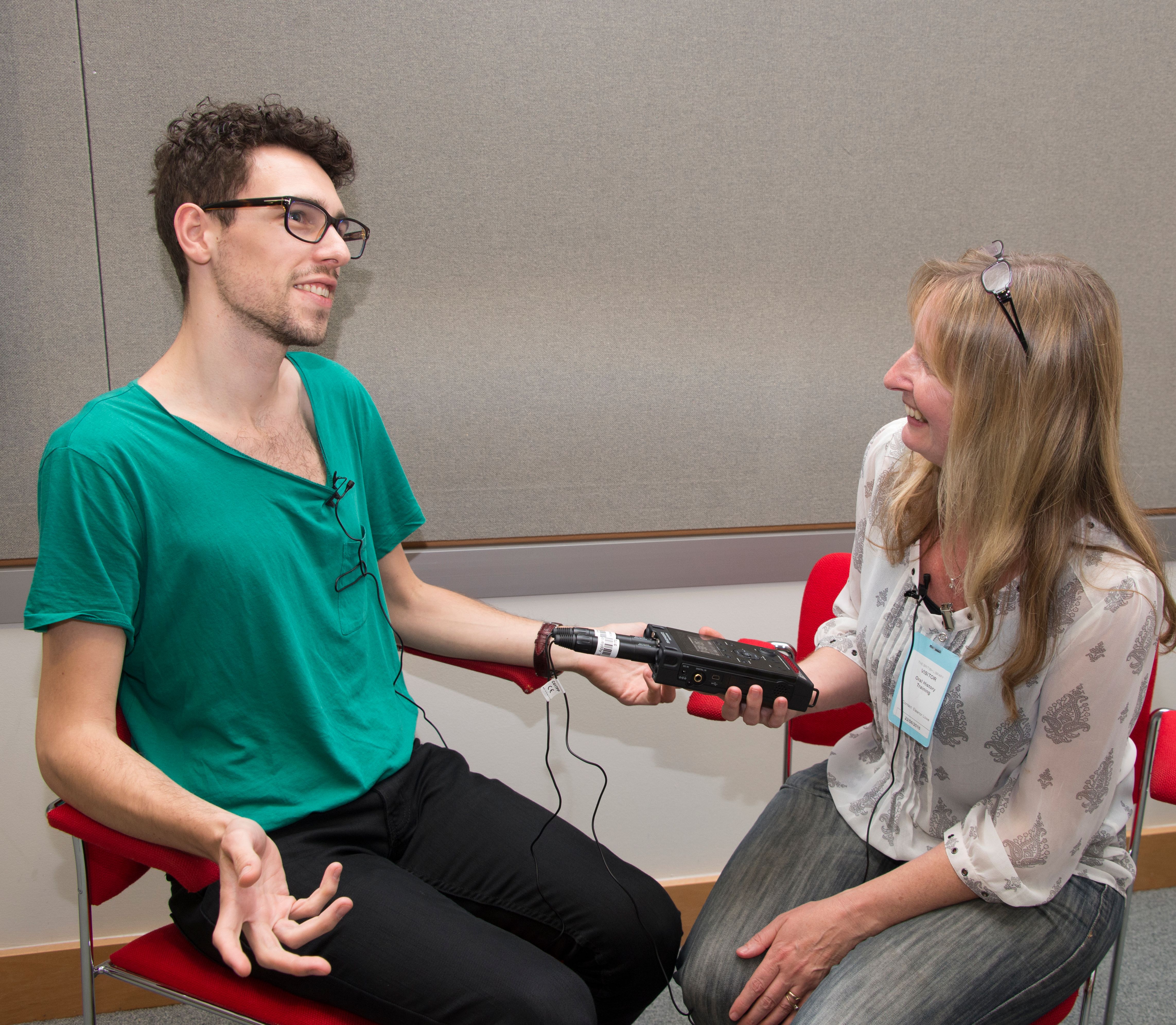 A woman holding a microphone in front of a man in a studio.