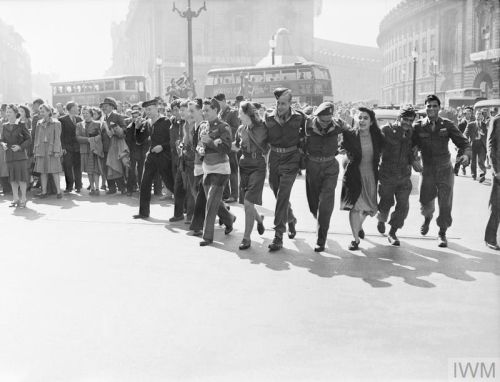 VJ Day celebrations in London's Piccadilly Circus with a row of soldiers and 2 buses in the background