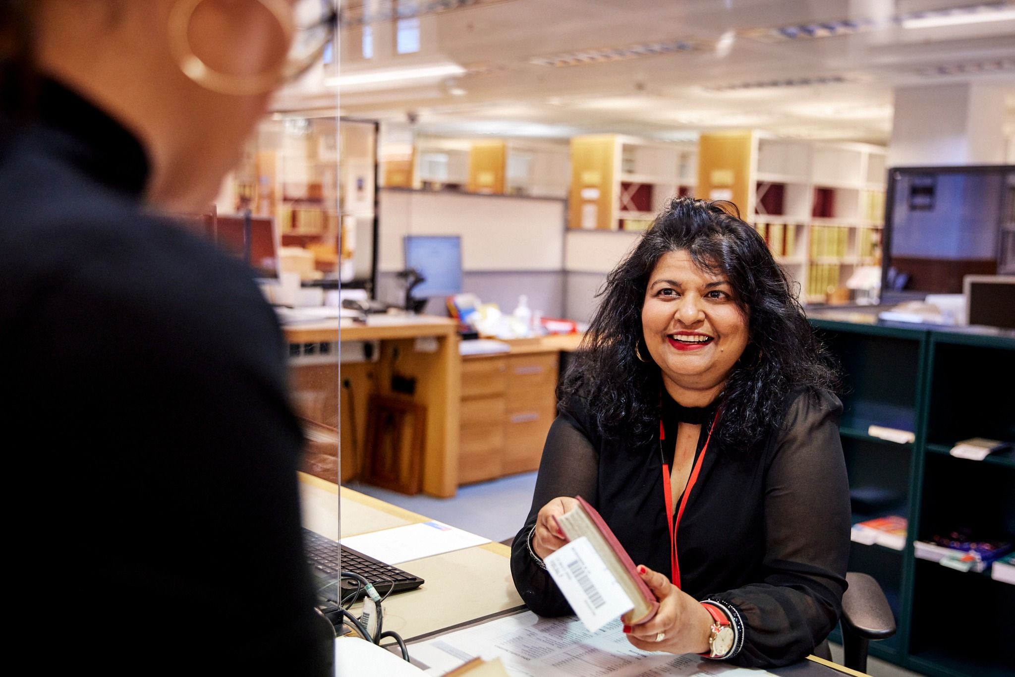 Library assistant issuing book to a reader.
