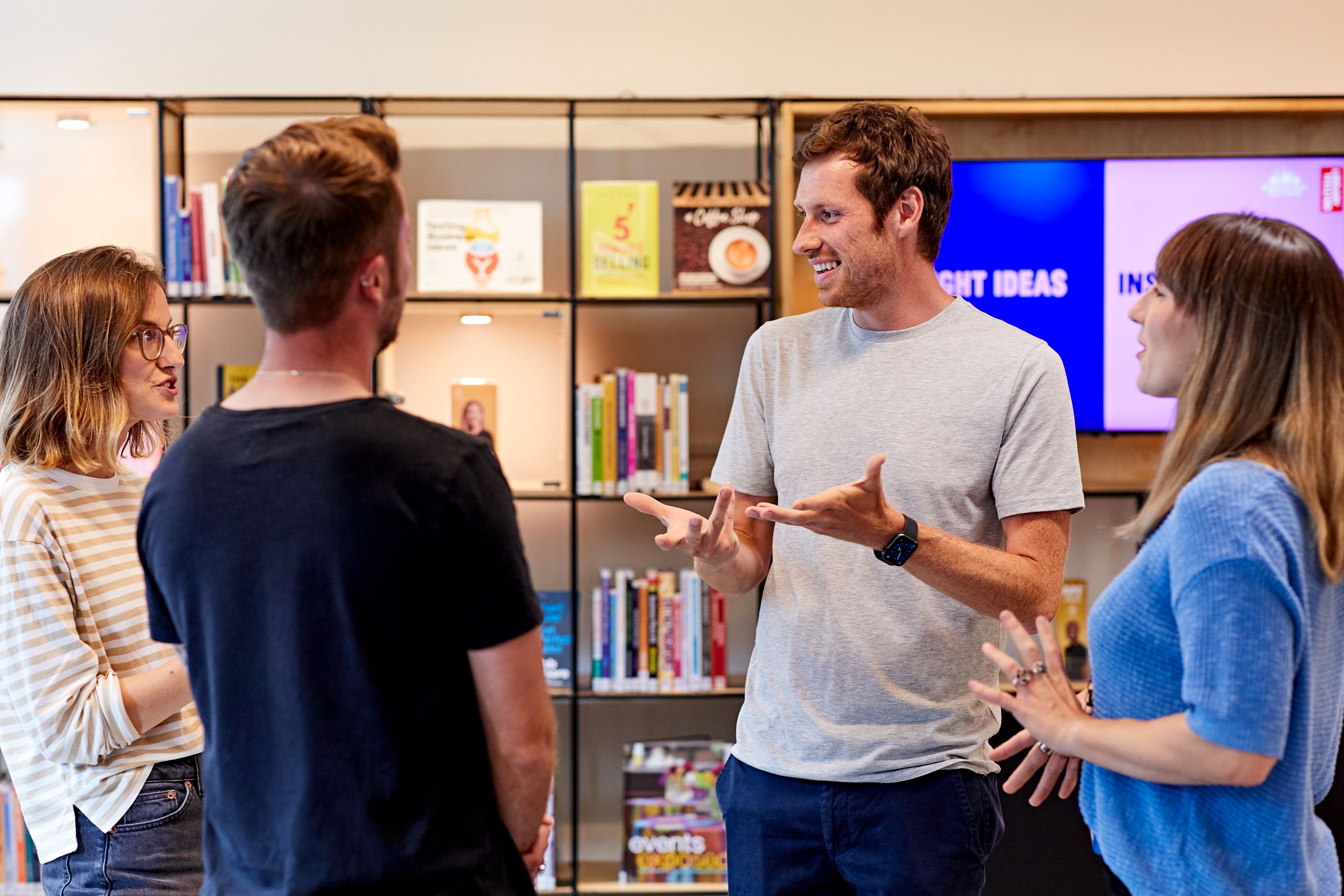 Four people standing and talking in a circle, in a business centre.
