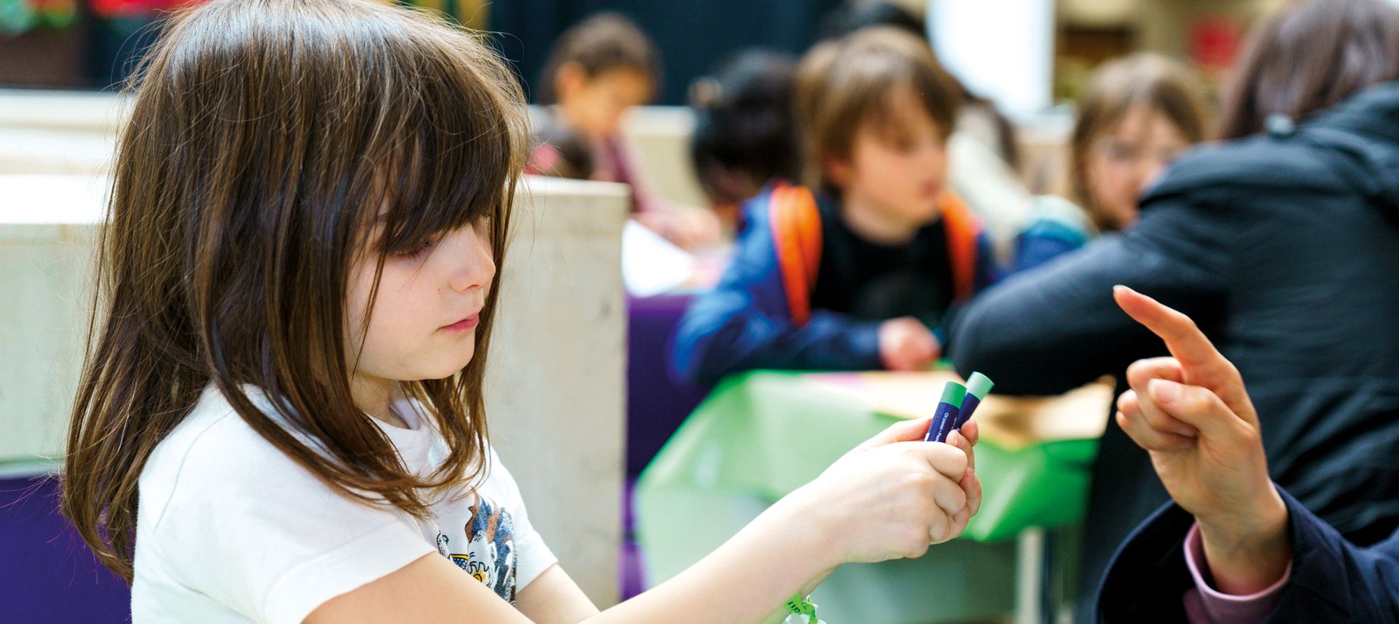 A young girl uses crayons for an activity, alongside other children, at the British Library in London.
