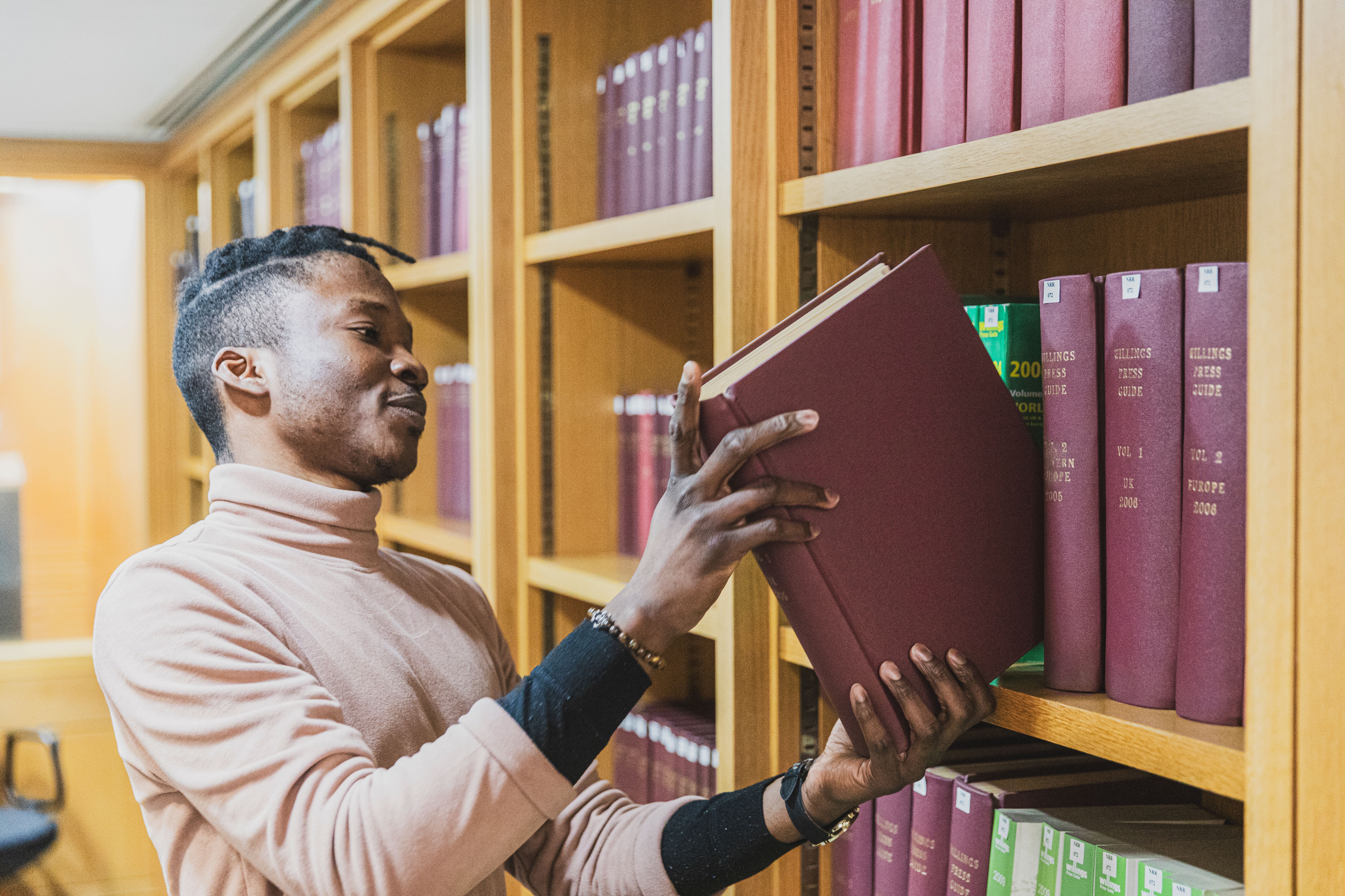 An apprentice carefully places a book on a book shelf at the British Library