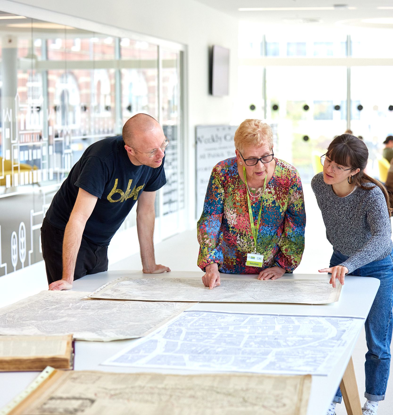 Three people stand around a map at a table in Nottingham Library.