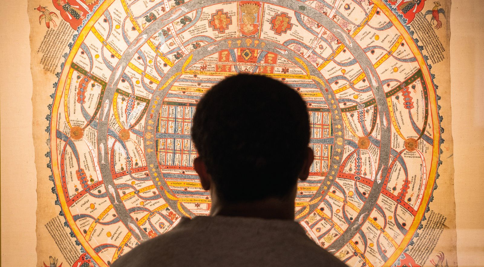 A visitor stands looking at a large collection item in a gallery at the British Library London.