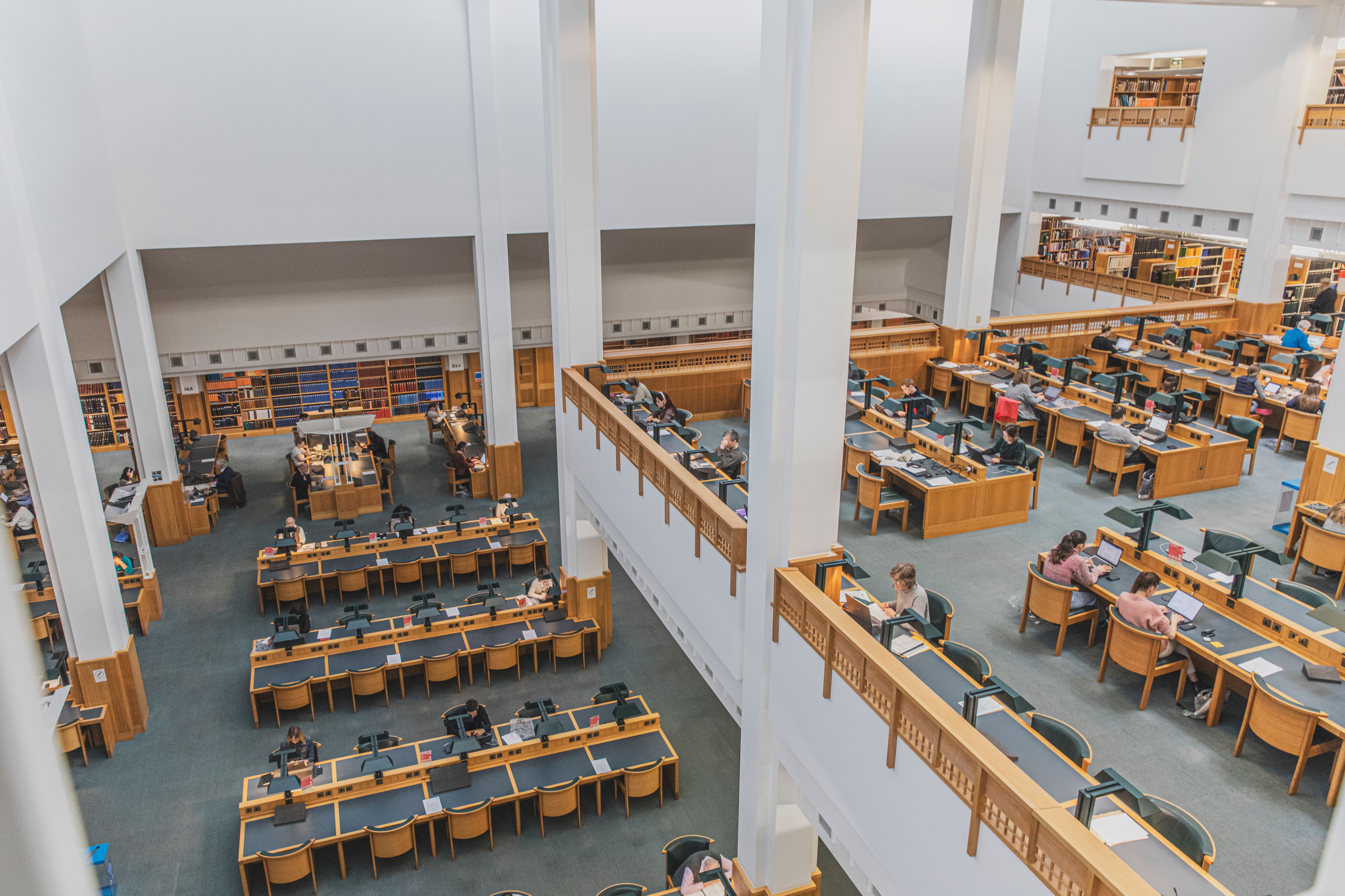 View from above of the Humanities Reading Room in the British Library in London, with people sat at desks.
