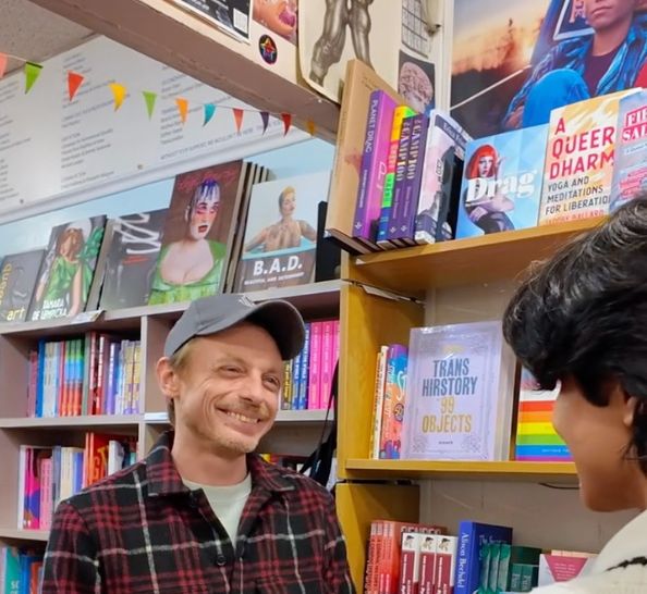 Man smiling in front of gay books.