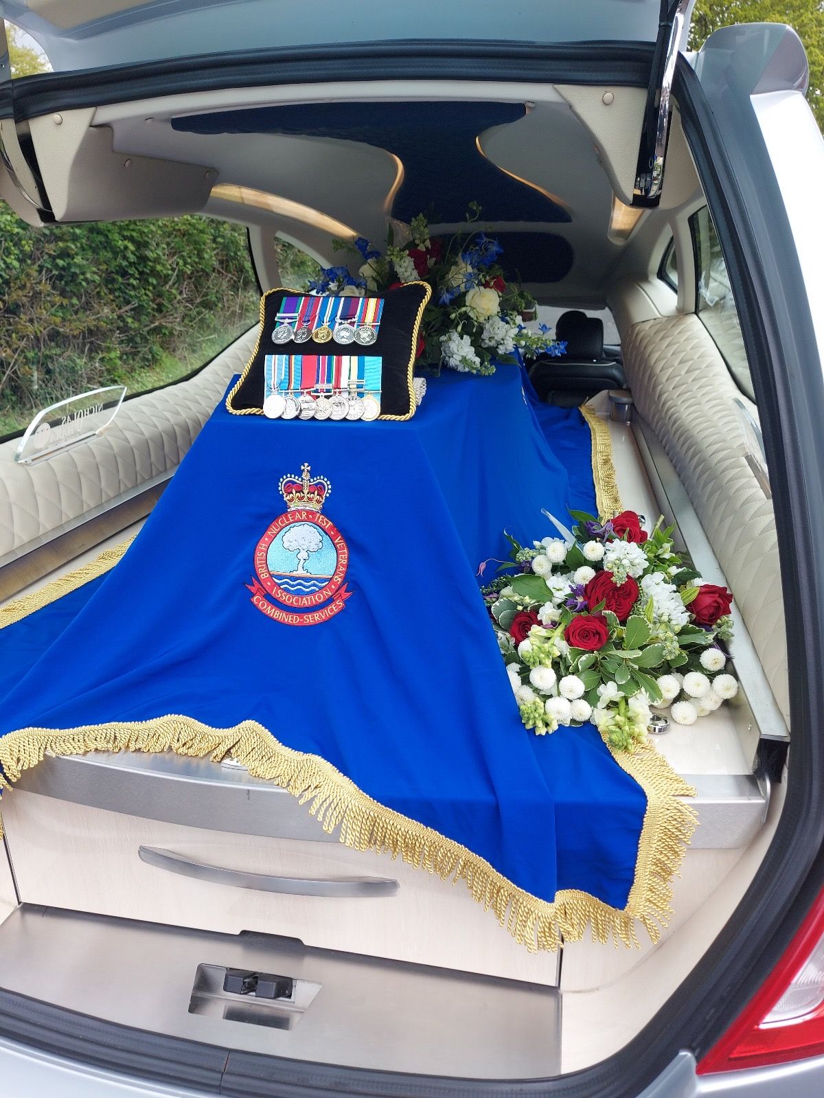 A blue coffin drape with a gold embroider and BNTVA crest.