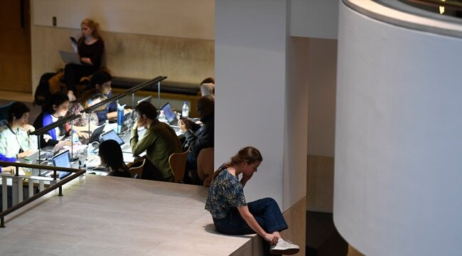 People studying in the public spaces of the British Library, while a young woman sits talking on the phone